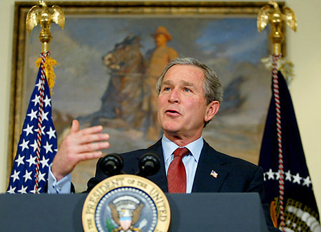 George W. Bush standing beneath a portrait of former U.S. President Theodore Roosevelt, Roosevelt Room, White House, February 18, 2003.